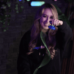 Young woman performing a yo-yo trick with a YoYoFactory yo-yo in a vibrant, colorful setting.